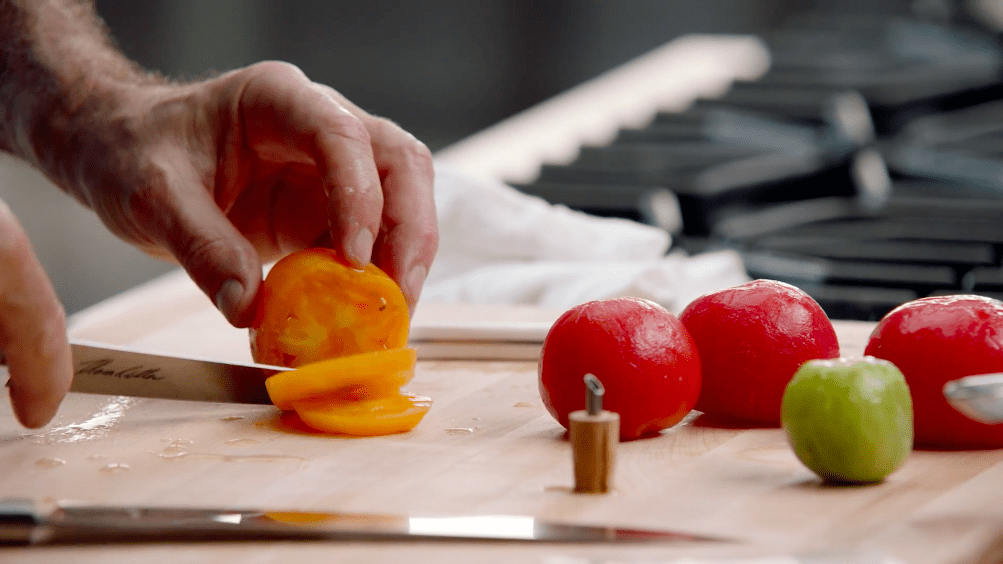 Image of Thomas Keller slicing peeled tomatoes in the Peeling: Tomatoes class of his MasterClass