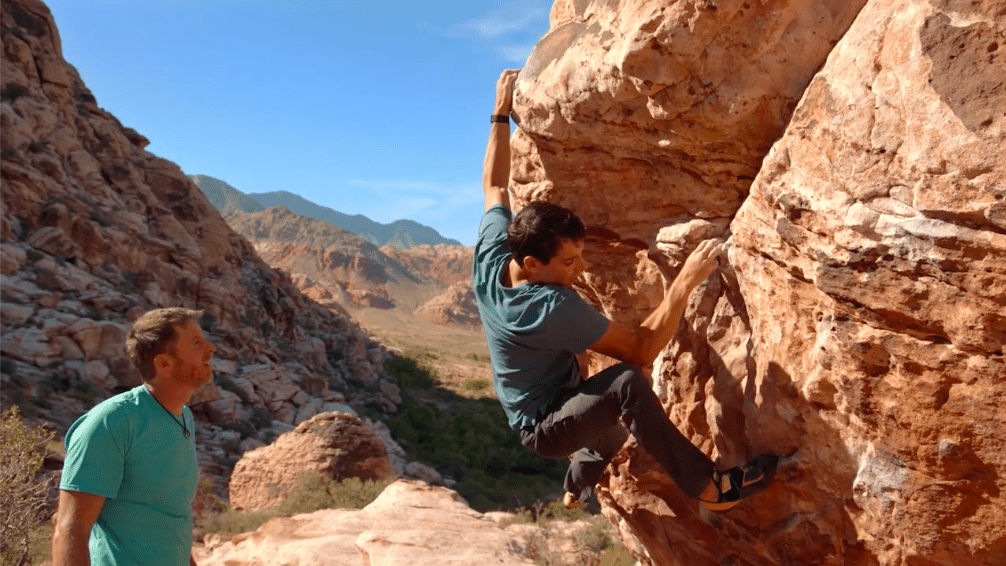 Image of Alex Honnold climbing a boulder while Tommy Caldwell spots him