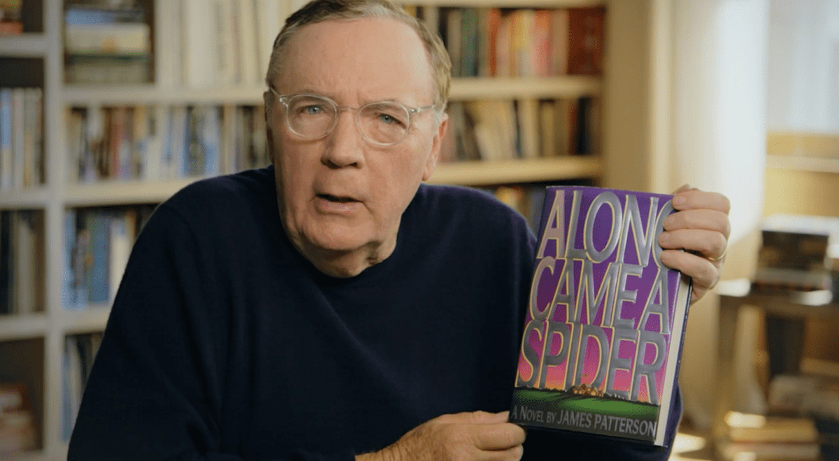 James Patterson holding a copy of his book Along Came a Spider