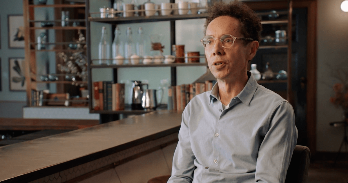 Malcolm Gladwell sits in front of a bar