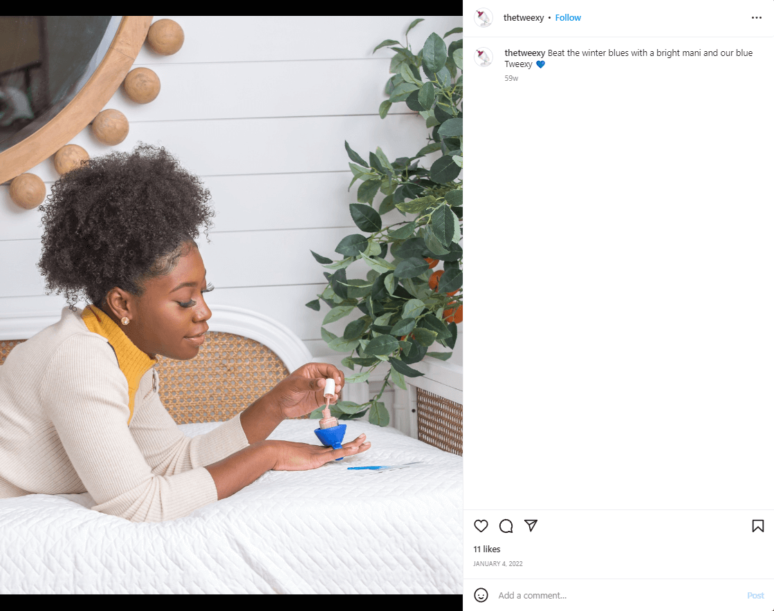 Woman laying on a bed painting nails using The Tweexy - a silicone ring that holds nail polish bottle in place. 